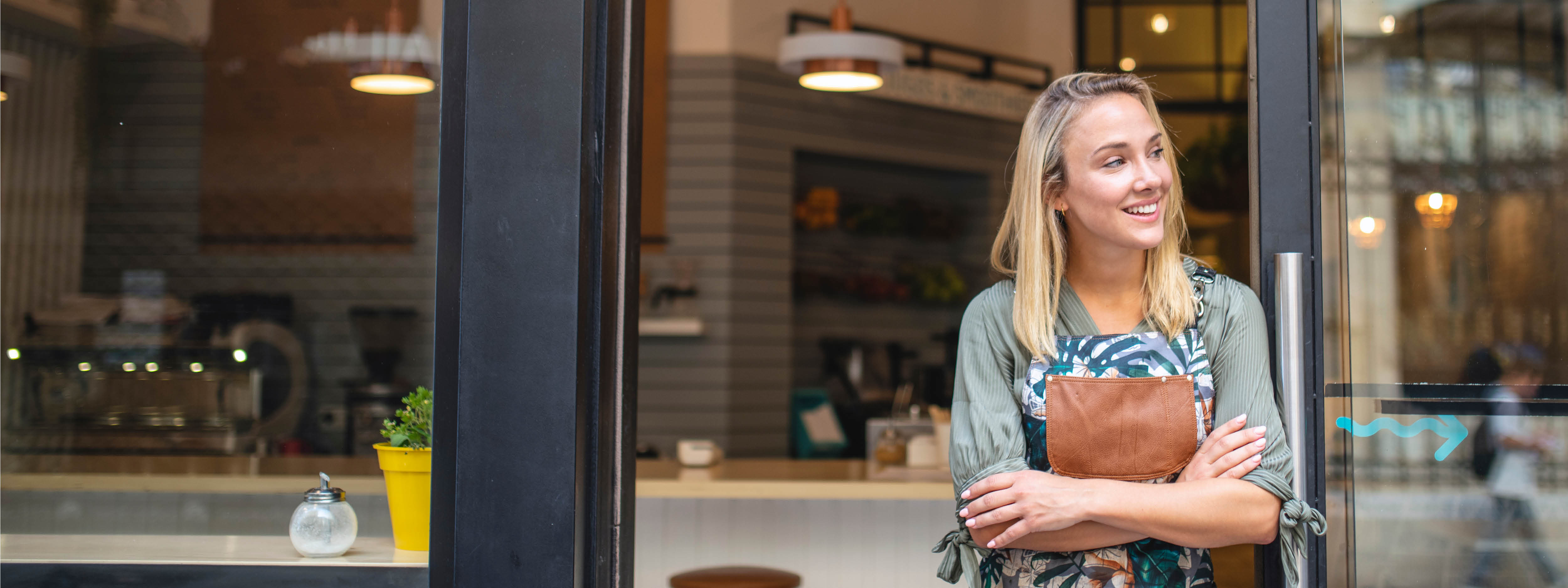 Woman standing in the doorway with her arms crossed hap